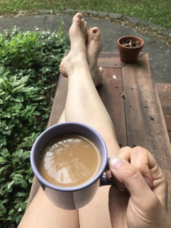 Kristen on a bench holding a coffee mug.